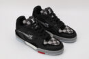 A pair of black low-top sneakers featuring white and grey checkerboard patterns on the tongue and side panels, a prominent white logo, and subtle red detailing on the sole, displayed against a light grey background.