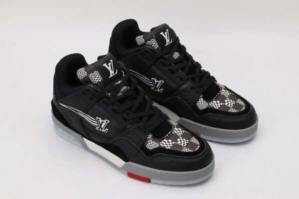 A pair of black low-top sneakers featuring white and grey checkerboard patterns on the tongue and side panels, a prominent white logo, and subtle red detailing on the sole, displayed against a light grey background.