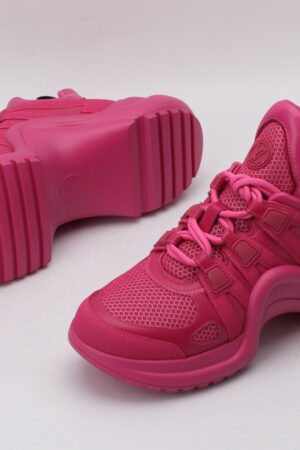 A pair of entirely pink low-top sneakers with a tonal embossed monogram pattern, matching pink laces, and a thick pink sole, displayed from a top-down angle against a plain white background.