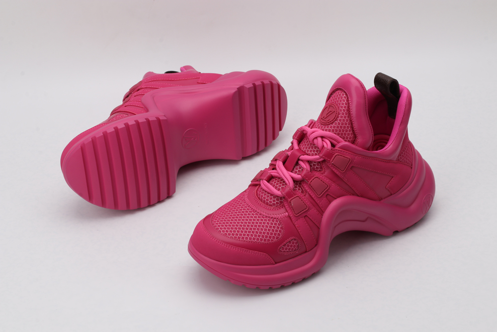 A pair of entirely pink low-top sneakers with a tonal embossed monogram pattern, matching pink laces, and a thick pink sole, displayed from a top-down angle against a plain white background.
