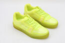 A pair of vibrant neon yellow/lime green translucent low-top sneakers with matching laces and a thick, clear-infused sole, set against a simple white background.