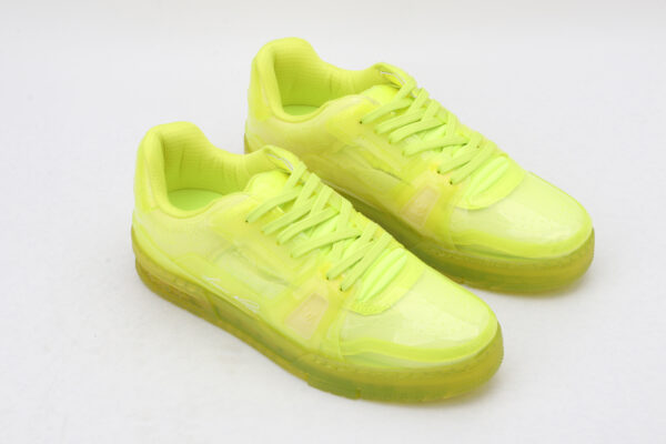 A pair of vibrant neon yellow/lime green translucent low-top sneakers with matching laces and a thick, clear-infused sole, set against a simple white background.