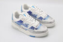 A pair of white low-top sneakers heavily embellished with shimmering silver rhinestones across the toe and sides, featuring bold blue rhinestone accents forming a logo and geometric patterns, set against a plain white background.