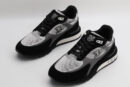 A pair of black, white, and grey athletic sneakers with prominent "LOUIS VUITTON PARIS" branding on the tongue, white mesh panels, black suede overlays, and grey accents on the sides, displayed from a top-down angle against a plain white background.