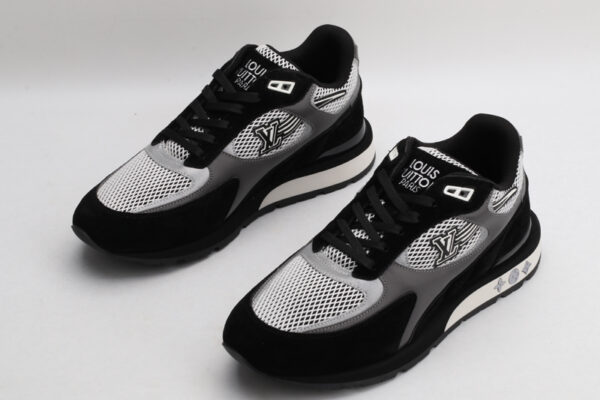 A pair of black, white, and grey athletic sneakers with prominent "LOUIS VUITTON PARIS" branding on the tongue, white mesh panels, black suede overlays, and grey accents on the sides, displayed from a top-down angle against a plain white background.