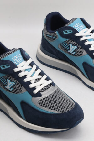A single athletic sneaker in shades of navy blue, light blue, and grey, featuring a textured mesh upper, suede overlays, white laces, and a layered sole with iconic patterns on the side, displayed from a side angle against a plain white background.