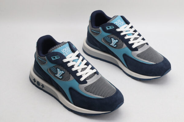 A single athletic sneaker in shades of navy blue, light blue, and grey, featuring a textured mesh upper, suede overlays, white laces, and a layered sole with iconic patterns on the side, displayed from a side angle against a plain white background.
