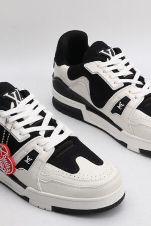 "A pair of EclipseStride Black and Off-White Sneakers, viewed from an angle, showcasing their low-top design, white laces, rich black suede panels, creamy off-white leather accents, and distinctive strap across the vamp with subtle branding