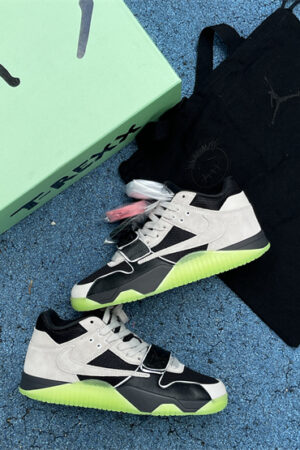 Pair of Jordan Jumpman Jack TR 'Travis Scott' sneakers in black, light grey, and neon green, showing the lateral reverse swoosh, resting on a light green surface with green plants in the background.