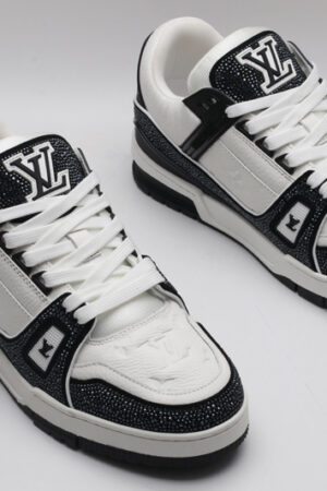 A single black and white Louis Vuitton LV Trainer sneaker, covered in glittering black crystal embellishments, with "VUITTON" written on the side strap