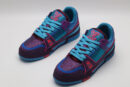 A pair of vibrant purple and blue Louis Vuitton LV Trainer sneakers, entirely covered in glittering multi-color crystal embellishments, with "VUITTON" visible on the outsole.