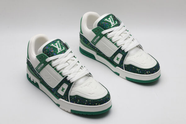 A single white and green Louis Vuitton LV Trainer sneaker, covered in glittering green crystal embellishments, with "VUITTON" written on the side strap