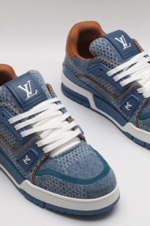 A single blue denim and tan Louis Vuitton LV Trainer Low-Top Sneaker, showcasing its textured denim upper, tan leather heel, and white laces