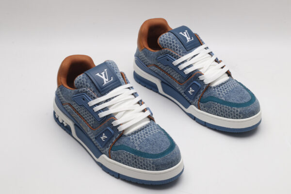 A single blue denim and tan Louis Vuitton LV Trainer Low-Top Sneaker, showcasing its textured denim upper, tan leather heel, and white laces