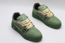 A single green Louis Vuitton LV Trainer Low-Top Sneaker, showcasing its embossed monogram on green leather, pink accents, and brown sole.