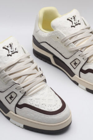 A single white Louis Vuitton LV Trainer Low-Top Sneaker, showcasing its embossed monogram on white leather and brown accents.