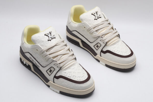 A single white Louis Vuitton LV Trainer Low-Top Sneaker, showcasing its embossed monogram on white leather and brown accents.