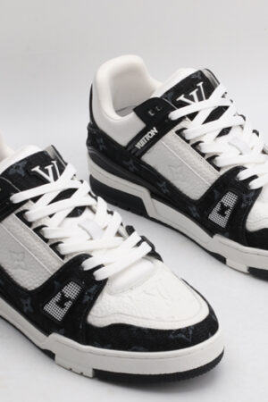 A pair of Louis Vuitton LV Trainer Low-Top Sneakers in white and black monogram, viewed from an elevated angle, showcasing both shoes with black monogram canvas panels and white leather details.