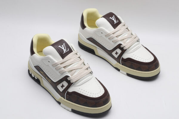 A pair of white and brown Louis Vuitton LV Trainer Low-Top Sneakers, featuring brown Louis Vuitton Monogram canvas and white leather.