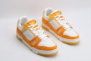 A pair of Louis Vuitton LV Trainer Low-Top Sneakers in white and orange monogram canvas, viewed from an elevated angle, showcasing both shoes with orange monogram canvas panels and white leather details.
