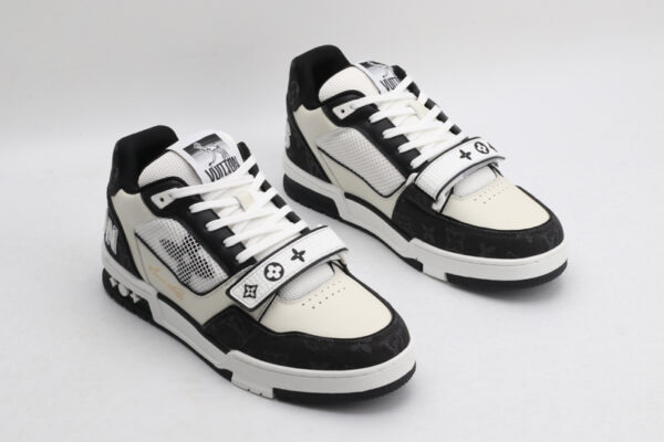 A pair of Louis Vuitton LV Trainer Mid-Top Sneakers in white and black monogram canvas, viewed from an elevated angle, showcasing both shoes with black monogram canvas panels, white and cream leather details, and a prominent white strap.