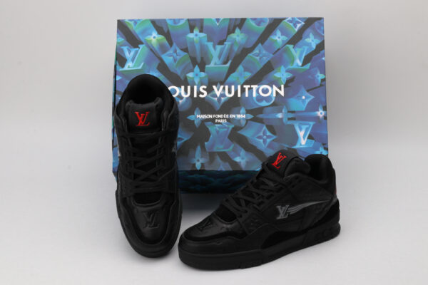 A pair of all-black Louis Vuitton LV Trainer sneakers with subtle grey LV monogram patterns and red accents on the tongue