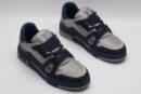 A pair of navy blue and silver Louis Vuitton LV Trainer sneakers, showcasing their bicolor design, textured panels, and robust outsole with "VUITTON" branding.