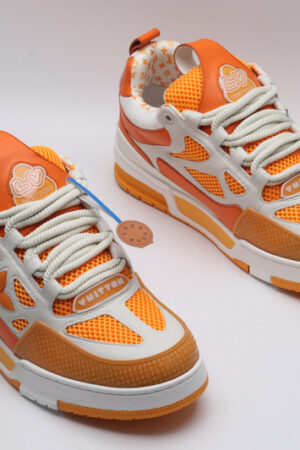 A single orange and white Louis Vuitton LV Trainer sneaker, showcasing its vibrant color blocking, mesh panels, and robust sole.