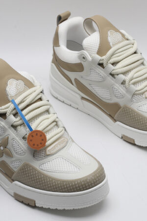 A single white and tan Louis Vuitton LV Trainer sneaker, showcasing its clean color blocking, mesh panels, and robust sole.