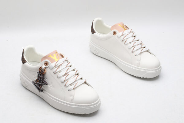 A pair of white Louis Vuitton Stellar Low-Top Sneakers with pink tongues and brown monogrammed heel tabs, viewed from a high angle