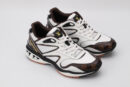 A pair of white athletic sneakers with brown monogram patterns on the toe and side, black outlining, white laces, and a multi-toned outsole with visible "VUITTON" branding on the heel, displayed against a light grey background