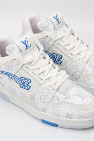 A pair of white high-top sneakers with subtle grey monogram patterns, prominent blue logos on the tongue and side, blue accents on the sole, and white laces, displayed against a light grey background.