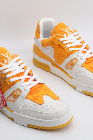 A pair of SunburstStride Orange and White Fashion Sneakers, viewed from the top, showcasing their low-top design, white laces, textured orange textile upper with a monogram pattern, white leather overlays, and a white rubber outsole with orange accents."