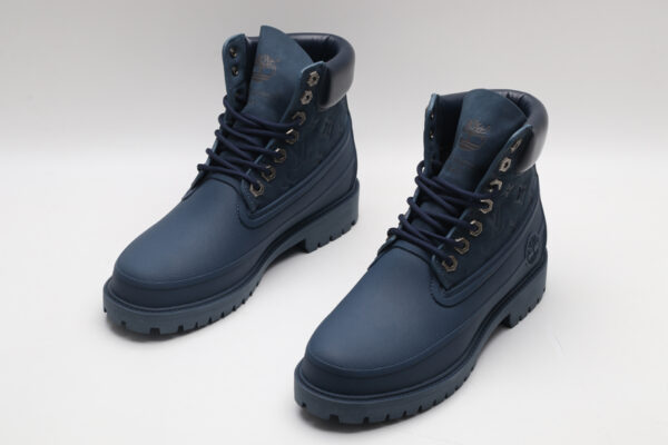 A pair of navy blue Timberland x Louis Vuitton collaborative waterproof boots, featuring the Timberland tree logo and subtle Louis Vuitton monogram debossing on the upper