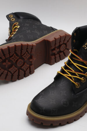 A pair of olive green Timberland x Louis Vuitton collaborative waterproof boots, featuring the Timberland tree logo and subtle Louis Vuitton monogram debossing on the upper.