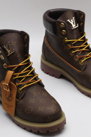A single brown Timberland x Louis Vuitton collaborative waterproof boot, featuring the all-over Louis Vuitton monogram pattern, yellow and red laces, and the Timberland tree logo.