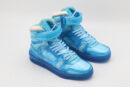 A pair of vibrant translucent azure blue high-top sneakers with white accents and a secure ankle strap, displayed against a clean white background.