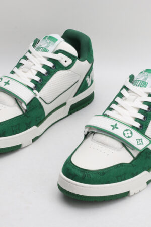 "A pair of VerdantStride Green and White Fashion Sneakers, viewed at an angle, showcasing their low-top design, white laces, vibrant green patterned textile upper, white leather overlays, and green and white rubber outsole with 'VUITTON' branding visible on one shoe."