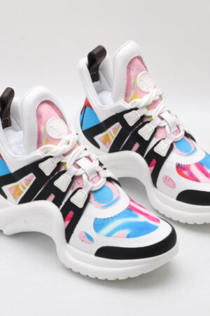 A pair of white chunky athletic sneakers with vibrant pink and blue swirl graphics, bold black structural overlays, white laces, a thick white sculptural sole, and mint green accents on the outsole, displayed against a plain white background.