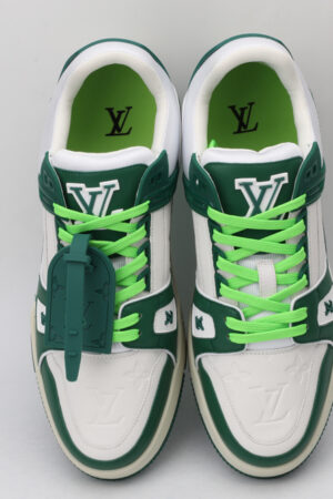 A pair of white low-top sneakers with bold green overlays, a prominent green logo on the side, vibrant green laces, and green accents on the outsole, displayed against a light grey background.