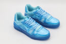 A pair of vibrant translucent blue low-top sneakers with matching laces and a clear blue sole, displayed against a clean white background.
