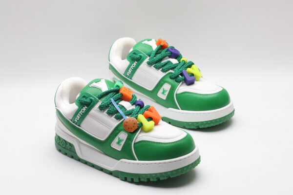 A single white and green Louis Vuitton LV Trainer Low-Top Sneaker, showcasing its full design from a slight angle, with bright orange and purple lace accents.