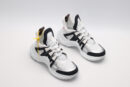 A pair of white and black chunky sneakers with a thick white sole. The shoes feature white mesh, black leather panels, and a subtle yellow branded tag. The sneakers are arranged on a clean white background, with one shoe positioned slightly ahead of the other.