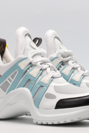 A pair of white, light blue, and black multi-panel chunky sneakers with a thick white sole, red and yellow accents, and a distinctive brown logo tag. The sneakers are photographed on a clean white background from a slightly elevated side angle.