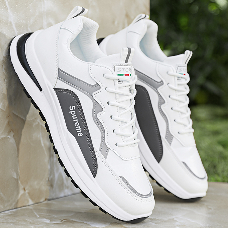 A pair of unisex running shoes with a multi-paneled design in black, white, and gray, featuring letter details on the side.