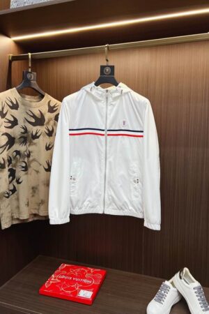 Black Moncler hooded nylon windbreaker jacket with a wide horizontal red, white, and blue tricolor stripe across the chest and the Moncler logo patch centered on it.