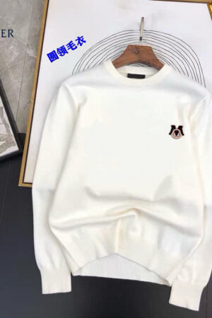 A pristine white crewneck sweater featuring a small designer-style logo on the chest, displayed on a flat surface with artistic backgrounds.