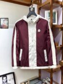 Front view of a burgundy and white hooded windbreaker jacket with sleeve stripes and a chest logo, hanging in a luxury retail setting.