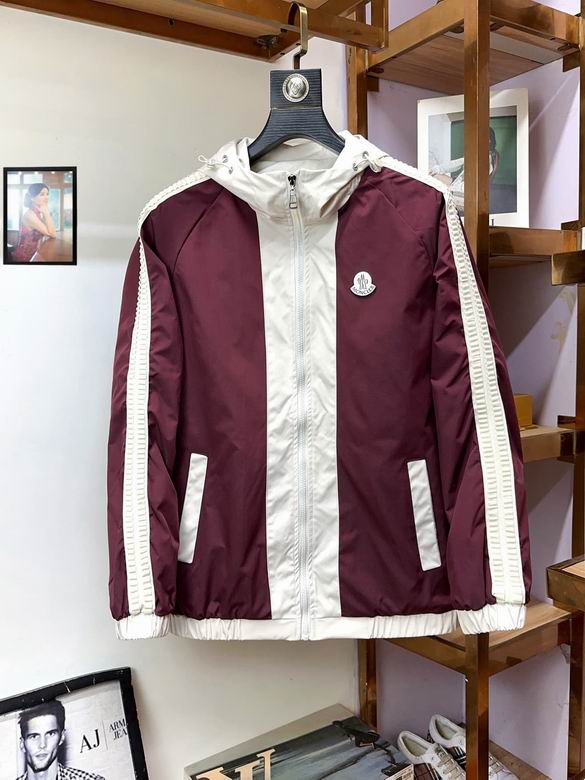 Front view of a burgundy and white hooded windbreaker jacket with sleeve stripes and a chest logo, hanging in a luxury retail setting.