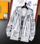 metallic windbreaker jacket with a hood, tricolor sleeve stripes, and a black circular logo patch hanging on a wooden hanger.